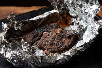 A piece of meat baked in the oven in foil. Home cooking.