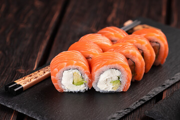 Sushi roll philadelphia with salmon and cucumber and cream cheese on black background. Sushi menu. Japanese food concept