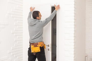 male workers carpenters installing interior door with a wooden frame at new luxury apartment