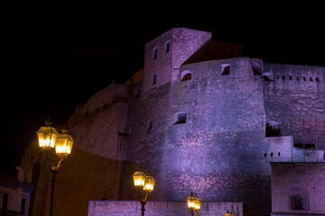 Night view of Castel dell'Ovo, a seafront castle located on a peninsula on the Gulf of Naples, Italy. Dark background.