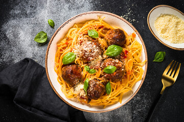 Pasta with Meatballs in tomato sauce, basil and parmesan on dark stone table. Top view with copy space.