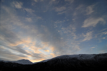 The sun setting behind snow covered mountains in Norway, winter