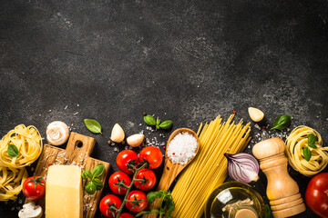 Pasta ingredients on black background. Raw Pasta, parmesan, fresh tomatoes and basil. Top view with...
