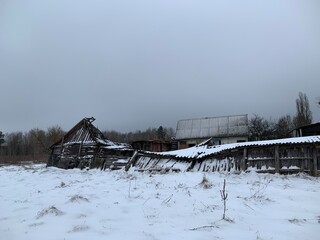 Wooden skewed house in the field. The wooden building fell into disrepair. Old, ruined house from a...