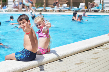 Children swim in the pool in the summer outdoors.