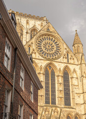 A view of the south entrance of York Minster from a brick building. A cloudy sky is abve.