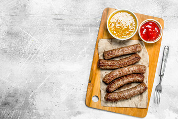 Grill sausages with different sauces .