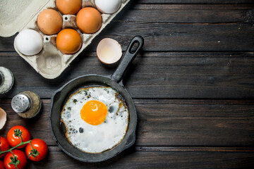 Fried egg in a pan with a cassette of fresh eggs.