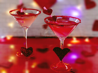 Cocktail glasses with red drink on background of red hearts, to celebrate Valentine's Day
