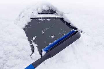 Close-up of cleaning a car window from snow, with a blue brush. Transport cleaning tools banner concept