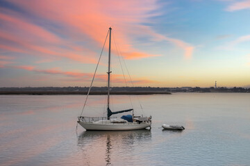 anchored sailboat with raft and solar panels at sunset