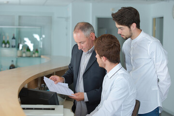 manager showing paperwork to hotel reception staff