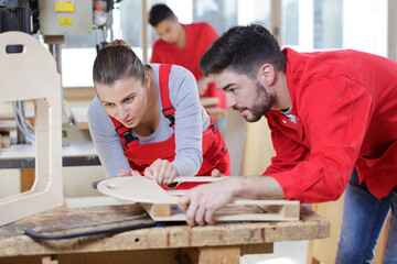 woman and man cutting wood with grinder during her apprenticeship
