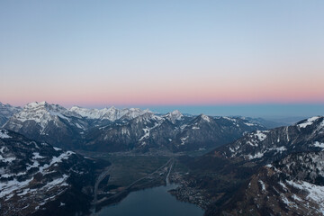 Fototapeta na wymiar Amazing sunrise with a pink horizon over the peaks of the Swiss Alps over a mountain lake in Glarus Canton.
