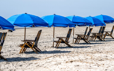 Sonnenliegen mit blauen Sonnenschirmen am Strand