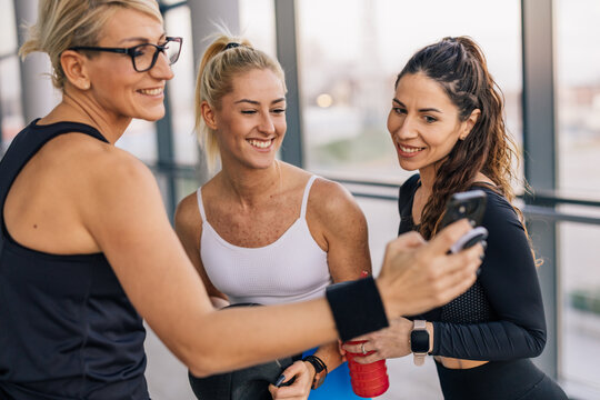 Three caucasian woman take photos in the gym using front camera