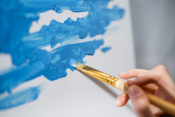 Cropped view of artist painting on canvas in studio