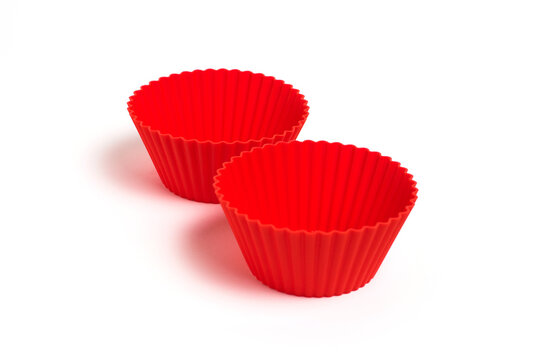 Red silicone molds for baking a cupcake on a white background