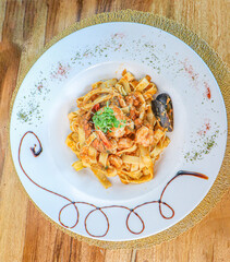 Penne pasta in tomato sauce with meat, tomatoes decorated with pea sprouts on a dark table