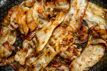Fried bacon in a frying pan.