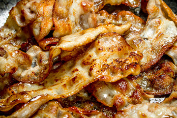Fried bacon in a frying pan.