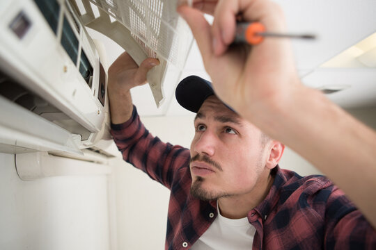 technician maintaining air-conditioning unit on the wall