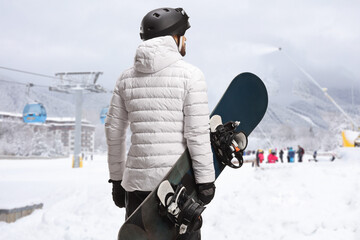 Fototapeta na wymiar Man with a snowboard looking at a ski resort