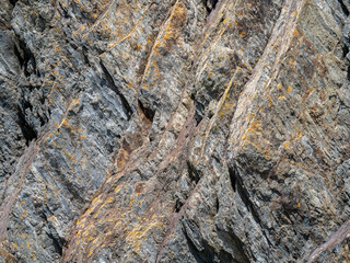 A variety of geological strata as a background. Stone texture, full frame. Brown and gray rock