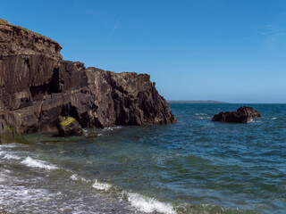 Fototapeta na wymiar A rock among the sea waters. Seaside landscape, rocky mountain beside body of water.