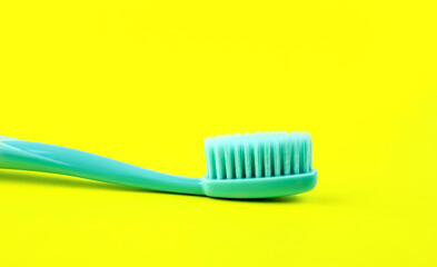Turquoise toothbrush on yellow background
