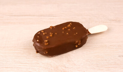 Chocolate ice cream on a wooden stick on a wooden background