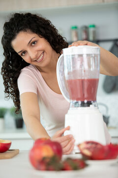 woman with modern blender chopping fruits and making smoothie