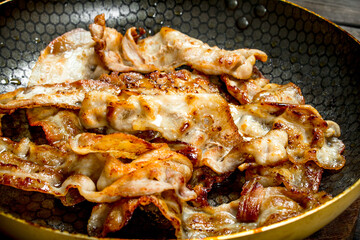 Fried bacon in a frying pan.