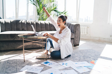 Happy woman sitting on floor at laptop placed on table