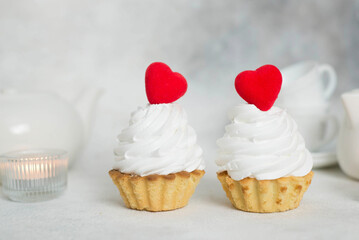 two cakes with red hearts and teapot, cups, candles on a gray background.