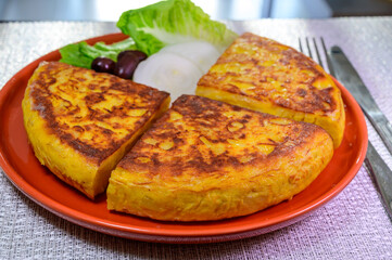 Spanish vegetarian food, portion of homemade tasty potato omelette tortilla de patatas with onion served in morning sunlights