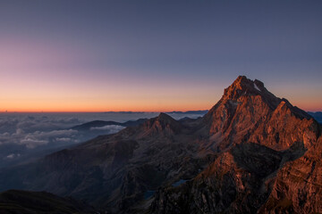 Obraz na płótnie Canvas Monviso (3481 m), a mountain in the western Italian Alps, stands out in the intense colors of dawn while the clouds downstream envelop it. 