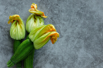 Three zucchini flowers piled on a stone background.