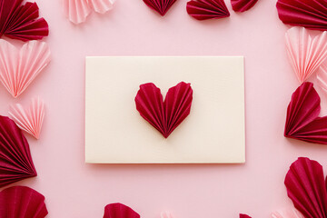 Valentines day flat lay. Stylish envelope with pink and red hearts composition on pink paper...