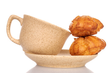 Two fragrant chouquettes on a ceramic saucer with a cup, on a white background.