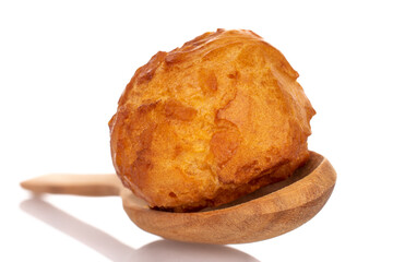 One sweet chouquette with a wooden spoon, close-up isolated on white.