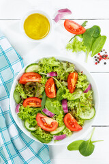 Mixed salad with fresh tomatoes healthy eating food from above portrait format on a wooden board