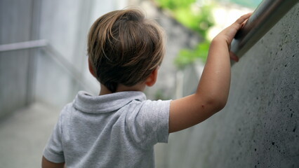 Child walking down stais holding handrail