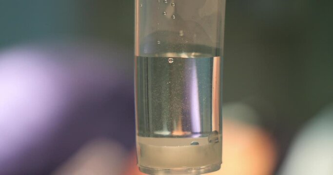 Close-up, slow motion. Dropper with slowly falling drops of a clear aqueous solution. In the operating room, an intravenous infusion of medication is carried out through a catheter close-up.