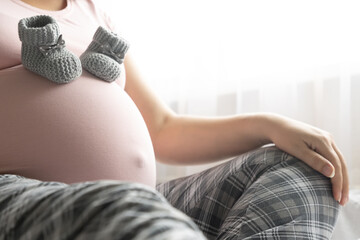 Two little wool booties on belly of pregnant woman. Healthy pregnacy.
