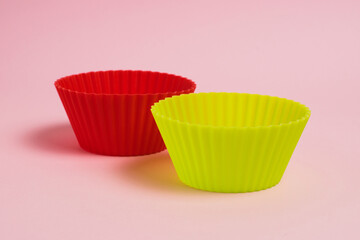 Red and yellow silicone cupcake molds on a pink paper background