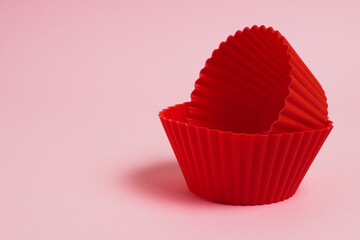 Red silicone molds for cupcakes on a pink paper background