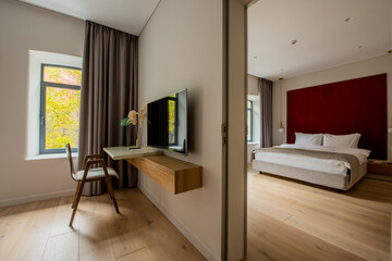 flat tv screen near wooden desk and chair next to bedroom in hotel room.