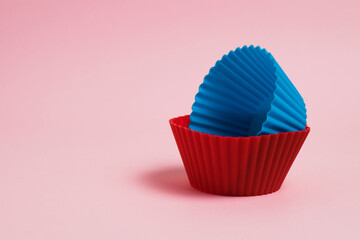 Blue and red silicone molds for cupcakes on a pink paper background