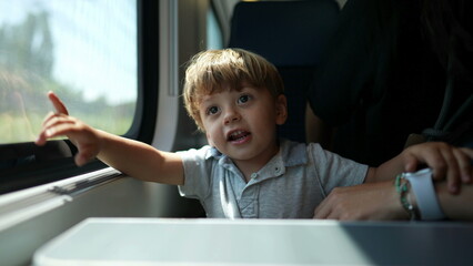 Child calling mother to look outside train window, seeing landscape passing by
